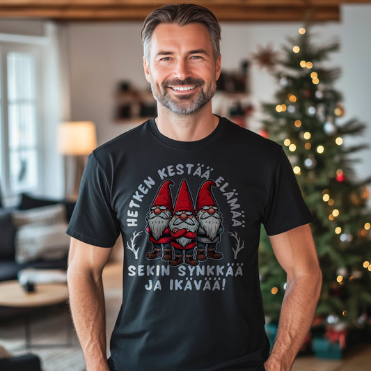 Hauska joulupaita, jossa on teksti 'Hetken kestää elämä, sekin synkkää ja ikävää' ja kolme tonttua vakavalla ilmeellä.