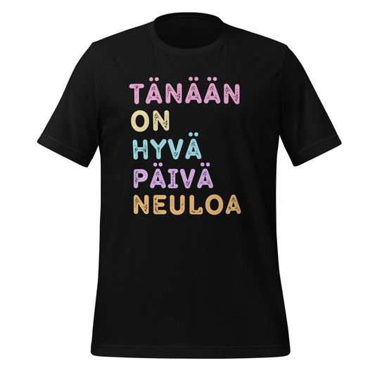 Musta t-paita, jossa lukee 'Tänään on hyvä päivä neuloa' pastellisävyisillä kirjaimilla mustalla pohjalla.