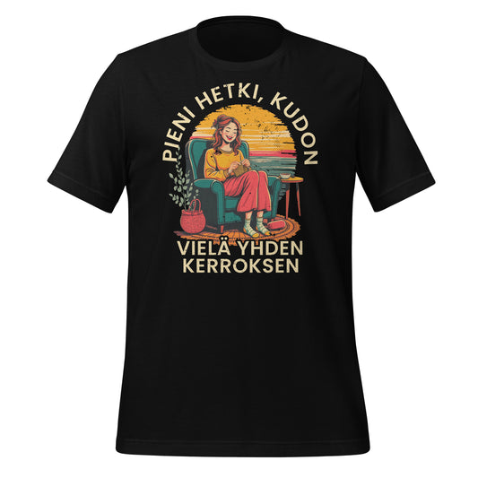 Musta t-paita, jossa on kutoja nojatuolissa, teksti 'Pieni hetki, kudon vielä yhden kerroksen' . Retro tyylinen design, joka on hyvä lahjaidea kutojalle.