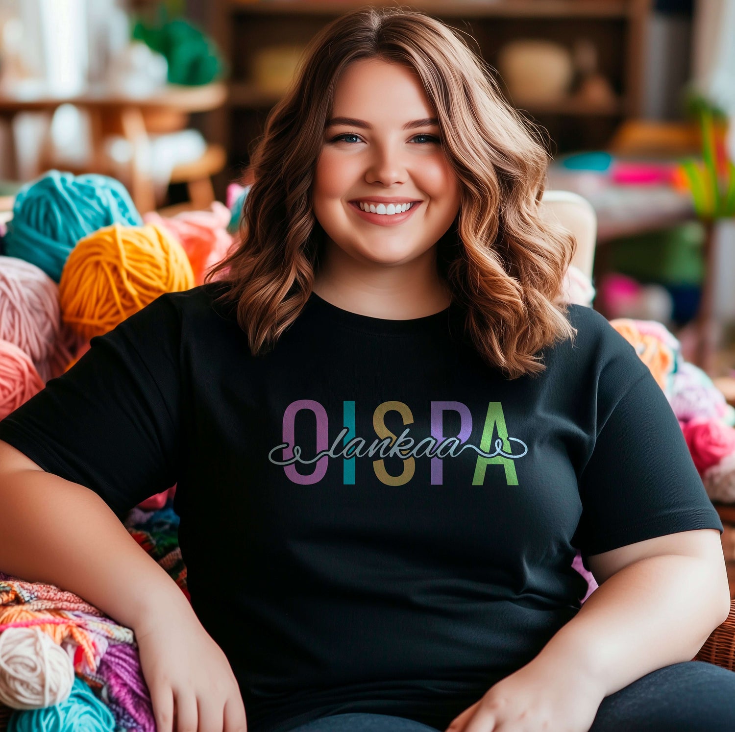 Hauskat paidat neulojille ja kutojille. Kuvassa nainen, joka istuu lankojen keskellä päällään musta t-paita, jossa lukee "oispa lankaa".